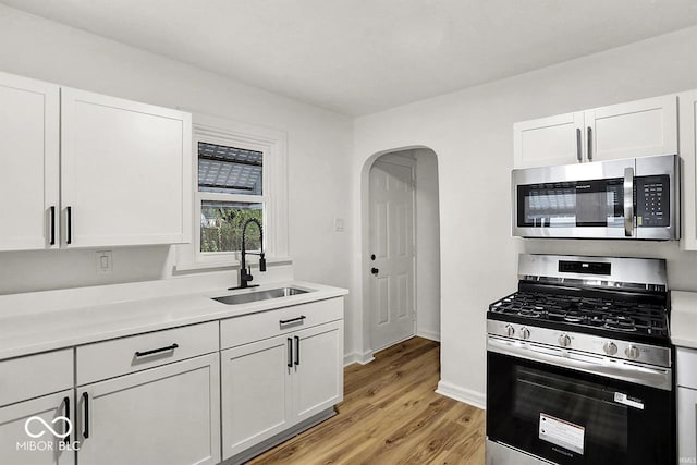 2015 S Hackley St, Muncie, IN 47302 - kitchen with stainless steel appliances, a sink, light wood-type flooring, arched walkways, and light countertops