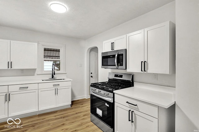 2015 S Hackley St, Muncie, IN 47302 - kitchen featuring appliances with stainless steel finishes, a sink, arched walkways, and white cabinets