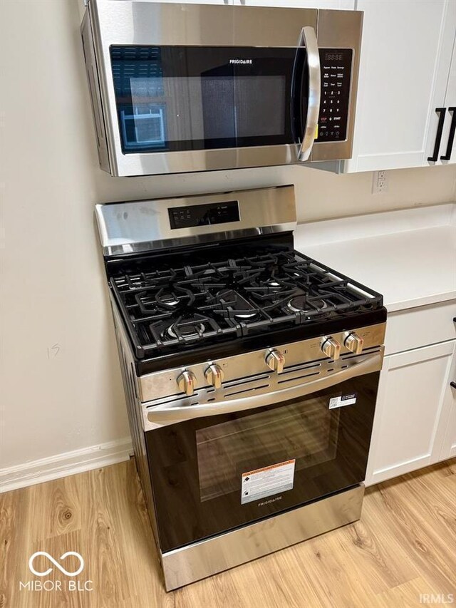 2015 S Hackley St, Muncie, IN 47302 - kitchen with appliances with stainless steel finishes, light wood-type flooring, white cabinetry, light countertops, and baseboards