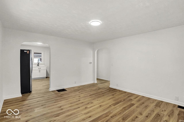 2015 S Hackley St, Muncie, IN 47302 - unfurnished room with arched walkways, light wood finished floors, baseboards, a textured ceiling, and a sink