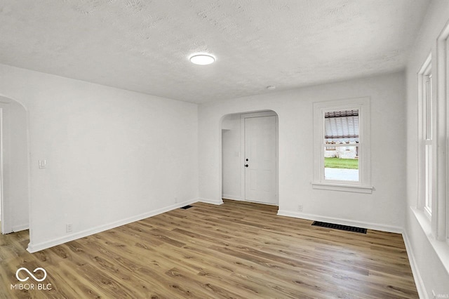 2015 S Hackley St, Muncie, IN 47302 - unfurnished room featuring arched walkways, wood finished floors, a textured ceiling, and baseboards