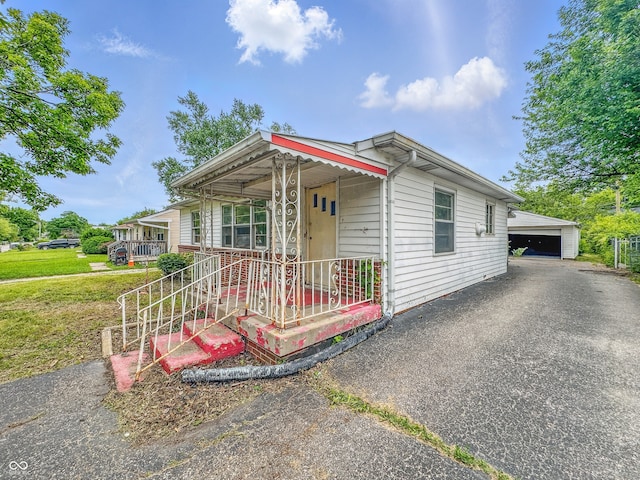 3615 N Dequincy St, Indianapolis, IN 46218 - view of front of house featuring covered porch, a front yard, and a detached garage