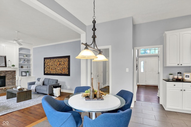 1410 Shadow Ct, Zionsville, IN 46077 - dining room with built in features, a ceiling fan, wood finished floors, and a fireplace