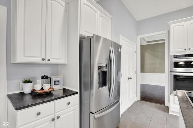 1410 Shadow Ct, Zionsville, IN 46077 - kitchen with appliances with stainless steel finishes, dark countertops, white cabinets, light tile patterned flooring, and wainscoting
