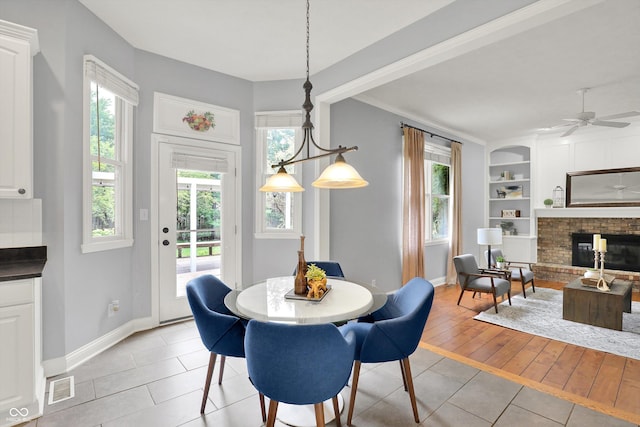 1410 Shadow Ct, Zionsville, IN 46077 - dining space featuring light tile patterned flooring, a brick fireplace, built in features, and plenty of natural light