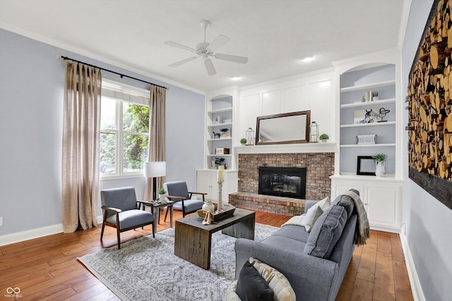 1410 Shadow Ct, Zionsville, IN 46077 - living area with a fireplace, wood-type flooring, a ceiling fan, built in shelves, and crown molding