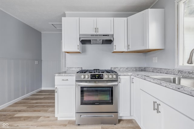 903 Sunset Dr, Lebanon, IN 46052 - kitchen featuring under cabinet range hood, stainless steel range with gas cooktop, a sink, light wood-type flooring, and white cabinets