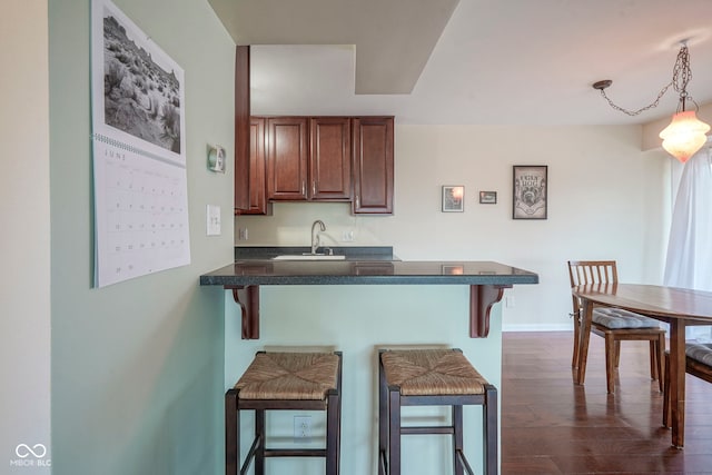 3965 N Meridian St Unit 3J, West, Indianapolis, IN 46208 - kitchen with dark countertops, a kitchen breakfast bar, a peninsula, a sink, and dark wood-style flooring