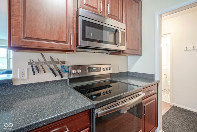 3965 N Meridian St Unit 3J, West, Indianapolis, IN 46208 - kitchen with appliances with stainless steel finishes, dark countertops, and brown cabinetry
