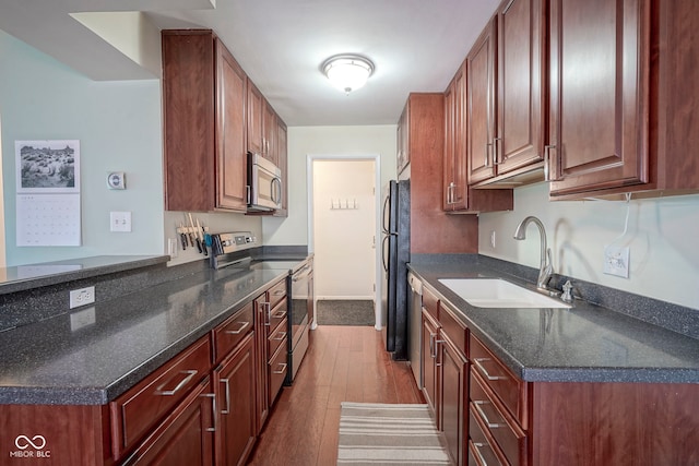3965 N Meridian St Unit 3J, West, Indianapolis, IN 46208 - kitchen featuring appliances with stainless steel finishes, a sink, dark wood finished floors, baseboards, and a peninsula