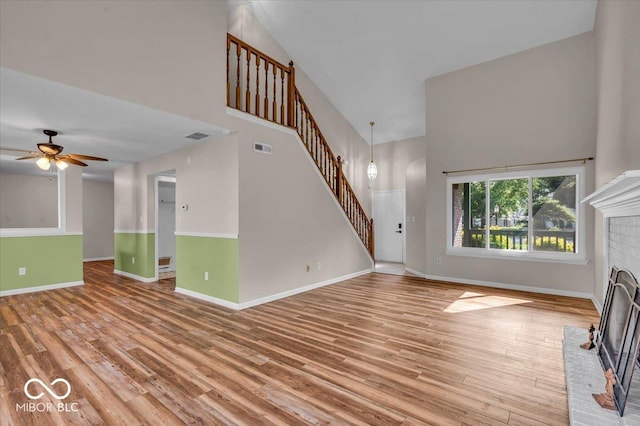 8908 Sunningdale Blvd, Indianapolis, IN 46234 - unfurnished living room with stairs, a high ceiling, a fireplace, wood finished floors, and a ceiling fan