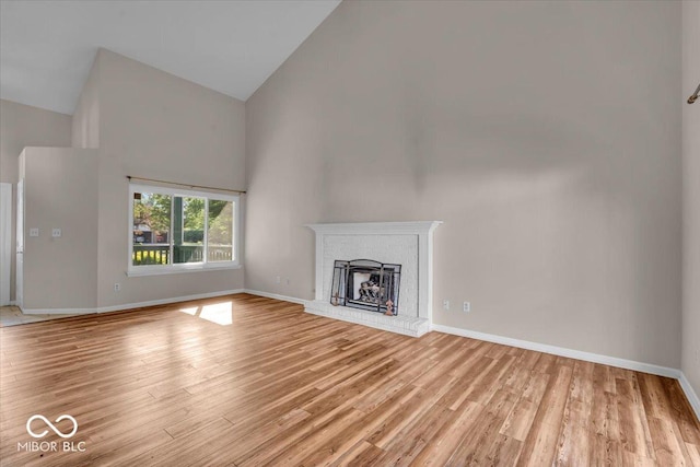 8908 Sunningdale Blvd, Indianapolis, IN 46234 - unfurnished living room featuring high vaulted ceiling, light wood finished floors, and a brick fireplace