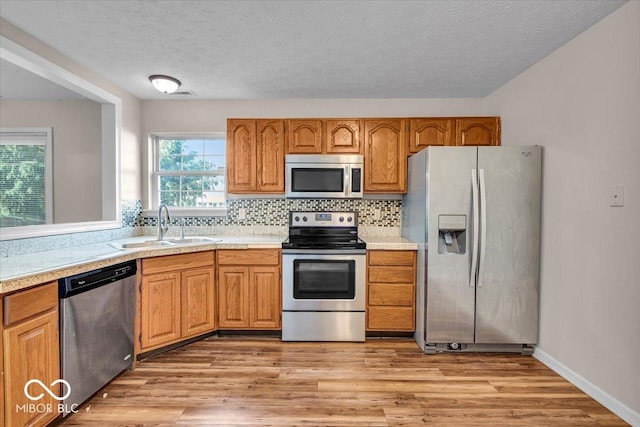 8908 Sunningdale Blvd, Indianapolis, IN 46234 - kitchen with stainless steel appliances, light countertops, light wood finished floors, decorative backsplash, and brown cabinets