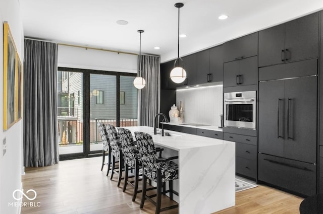 420 Monon Wy Dr, Carmel, IN 46032 - kitchen with stainless steel oven, paneled built in fridge, a sink, light wood-style floors, and a kitchen breakfast bar