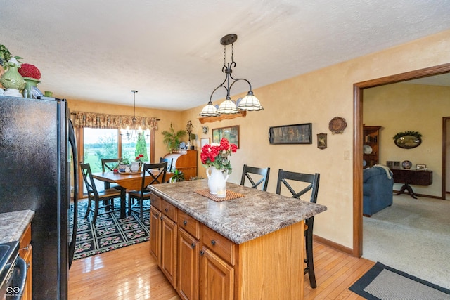 1607 Michelle Mnr, Danville, IN 46122 - kitchen with freestanding refrigerator, a center island, light wood finished floors, and a breakfast bar