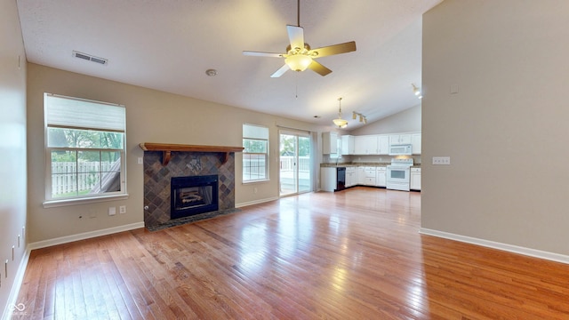 3959 Towhees Dr, Indianapolis, IN 46237 - unfurnished living room featuring light wood-style floors, a ceiling fan, baseboards, a tiled fireplace, and vaulted ceiling