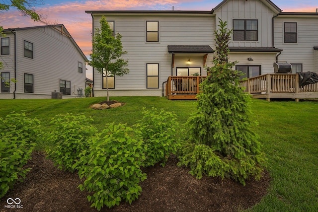 17551 Gruner Way, Westfield, IN 46062 - back of property at dusk with a wooden deck, a yard, board and batten siding, and central AC unit
