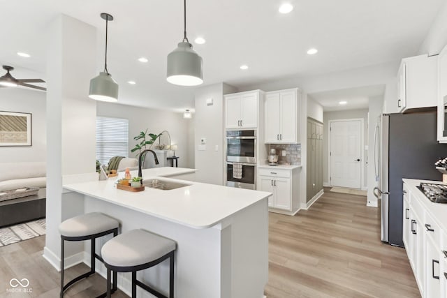 17551 Gruner Way, Westfield, IN 46062 - kitchen featuring a sink, stainless steel appliances, a breakfast bar area, white cabinetry, and light wood-style flooring