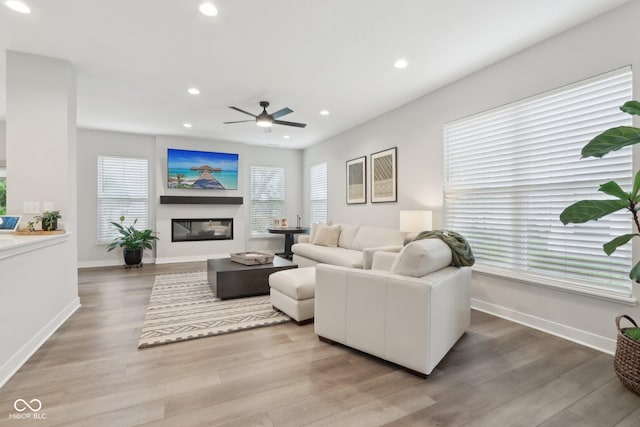17551 Gruner Way, Westfield, IN 46062 - living area with light wood-type flooring, recessed lighting, a glass covered fireplace, a ceiling fan, and baseboards