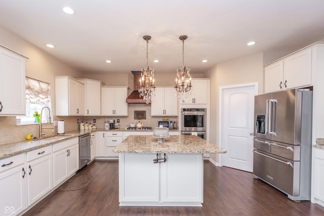 1661 Devonshire Ave, Avon, IN 46123 - kitchen featuring appliances with stainless steel finishes, a sink, a kitchen island, wall chimney exhaust hood, and a chandelier