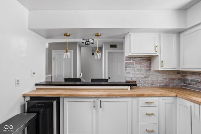 2263 Rome Dr, Indianapolis, IN 46228 - kitchen featuring butcher block countertops, backsplash, white cabinets, and decorative light fixtures