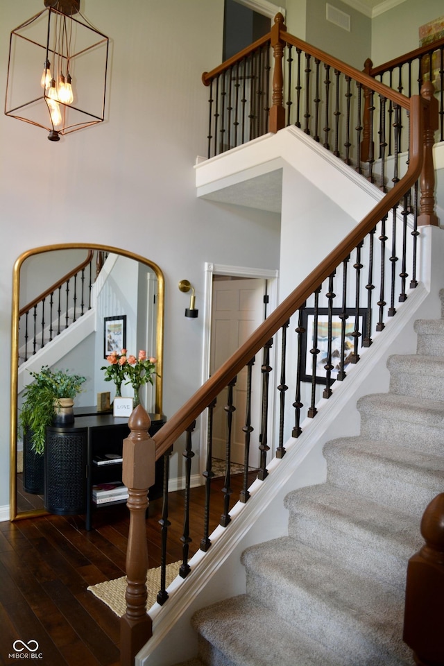 6862 Riverside Way, Fishers, IN 46038 - stairway featuring wood-type flooring, a towering ceiling, baseboards, a chandelier, and crown molding