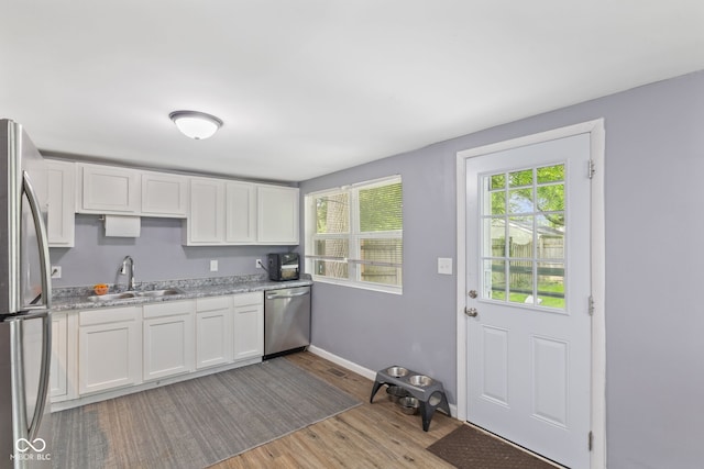 938 N Tuxedo St, Indianapolis, IN 46201 - kitchen featuring a sink, appliances with stainless steel finishes, wood finished floors, and white cabinetry
