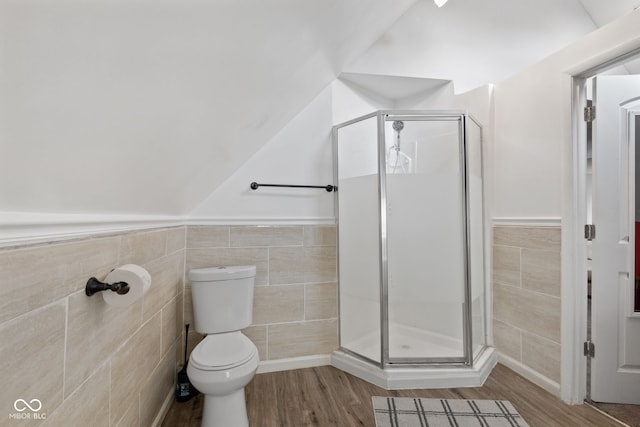 938 N Tuxedo St, Indianapolis, IN 46201 - bathroom with tile walls, wood finished floors, a stall shower, toilet, and a wainscoted wall