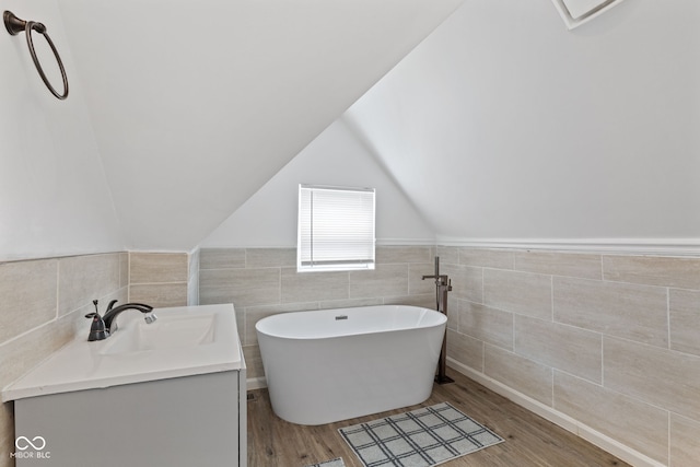 938 N Tuxedo St, Indianapolis, IN 46201 - full bath with tile walls, a freestanding bath, wood finished floors, vanity, and vaulted ceiling