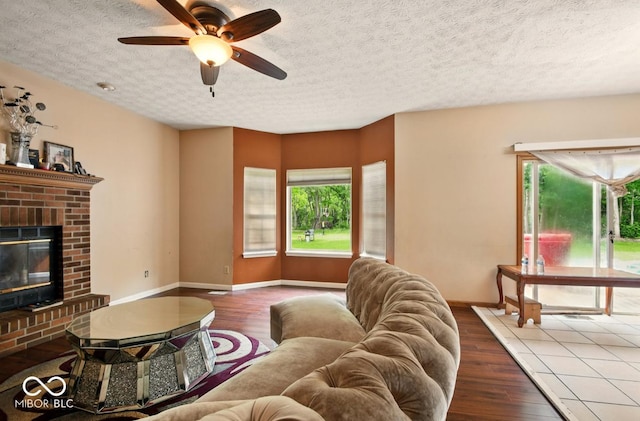 6396 Granny Smith Ln, Avon, IN 46123 - living room with wood finished floors, ceiling fan, baseboards, a textured ceiling, and a brick fireplace
