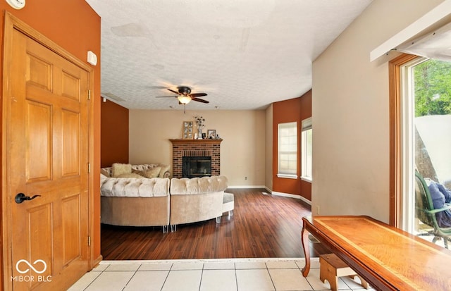 6396 Granny Smith Ln, Avon, IN 46123 - living room with ceiling fan, wood finished floors, a brick fireplace, a textured ceiling, and baseboards
