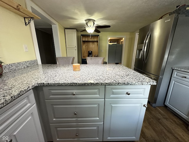 12967 N County Road 825 E, Roachdale, IN 46172 - kitchen with stainless steel fridge, dark wood-style flooring, ceiling fan, a peninsula, and light stone countertops