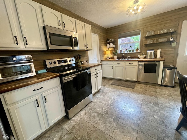 2210 Bridlewood Dr, Franklin, IN 46131 - kitchen featuring appliances with stainless steel finishes, wooden counters, open shelves, a textured ceiling, and white cabinetry