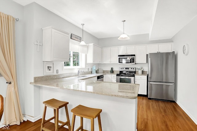 10965 Fairway Ridge Ln, Fishers, IN 46037 - kitchen with appliances with stainless steel finishes, a peninsula, white cabinetry, wood finished floors, and light stone counters