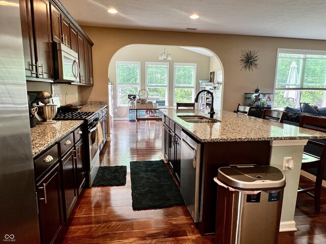1518 Valdarno Dr, Greenwood, IN 46143 - kitchen with appliances with stainless steel finishes, a sink, arched walkways, dark wood-type flooring, and an island with sink