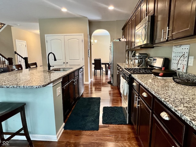 1518 Valdarno Dr, Greenwood, IN 46143 - kitchen featuring stainless steel appliances, a sink, arched walkways, dark wood-type flooring, and a breakfast bar area