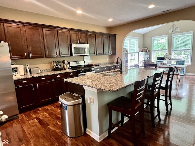1518 Valdarno Dr, Greenwood, IN 46143 - kitchen featuring stainless steel appliances, arched walkways, a sink, dark wood finished floors, and light stone countertops