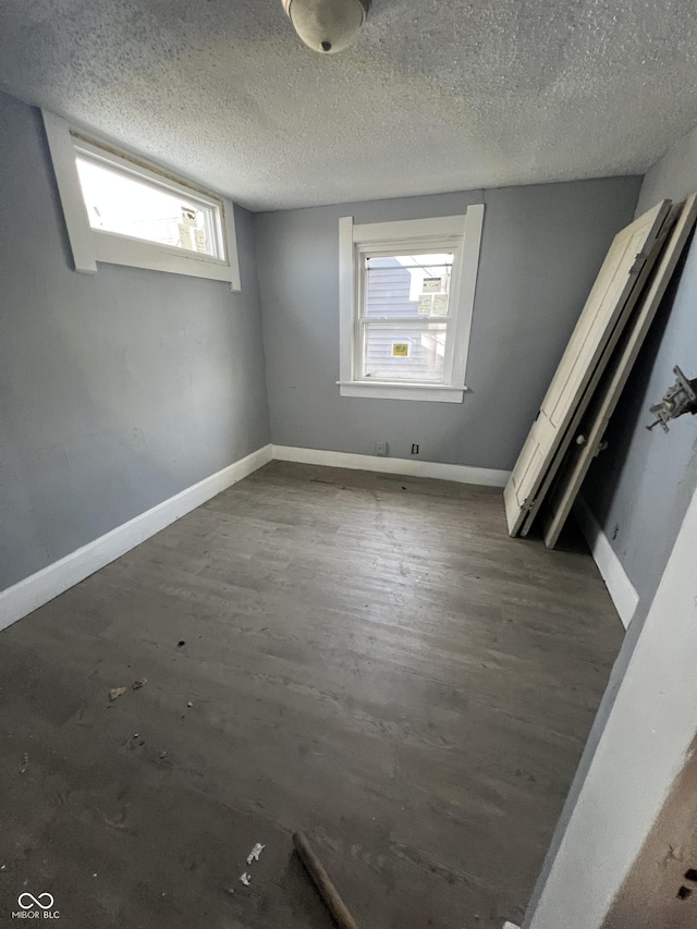 409 Parkway Ave, Indianapolis, IN 46225 - unfurnished bedroom with multiple windows, wood finished floors, a textured ceiling, and baseboards