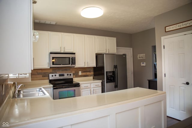 kitchen featuring appliances with stainless steel finishes, a sink, backsplash, light countertops, and white cabinets