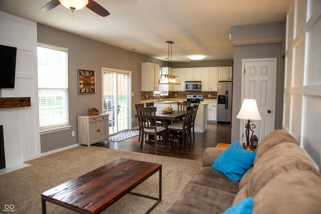 living room with ceiling fan and baseboards
