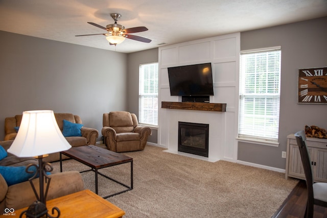 living room featuring a ceiling fan, a tile fireplace, and baseboards