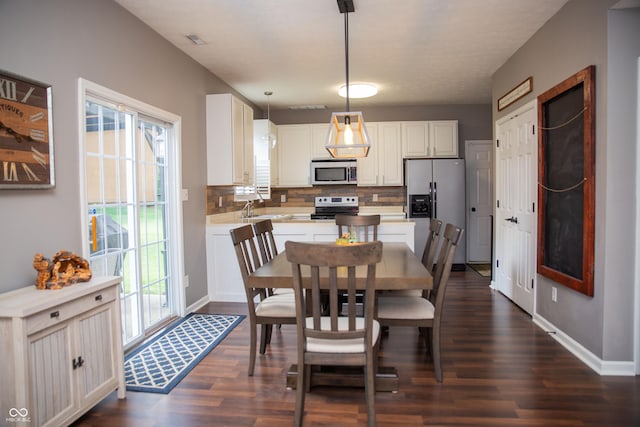 dining room with dark wood-style floors, plenty of natural light, and baseboards