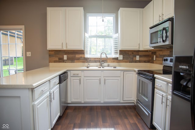 kitchen featuring stainless steel appliances, a sink, tasteful backsplash, white cabinetry, and a peninsula