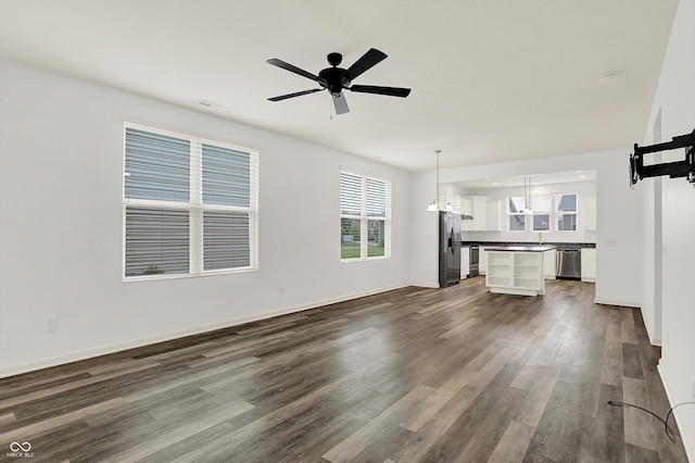 5125 Lilium Dr, Plainfield, IN 46168 - unfurnished living room featuring dark wood-style flooring, healthy amount of natural light, a chandelier, and ceiling fan
