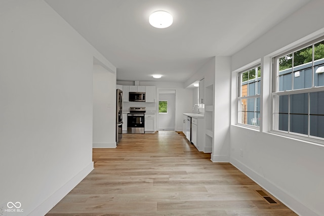 1411 N Grant Ave, Indianapolis, IN 46201 - corridor with a sink, baseboards, and light wood-type flooring
