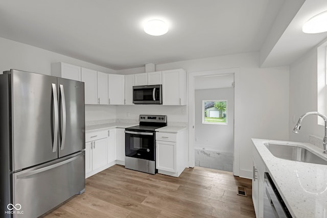 1411 N Grant Ave, Indianapolis, IN 46201 - kitchen featuring appliances with stainless steel finishes, a sink, light stone countertops, and white cabinets