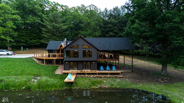 3463 Plum Creek Rd, Nashville, IN 47448 - back of house with a deck with water view, a yard, a chimney, roof with shingles, and a view of trees