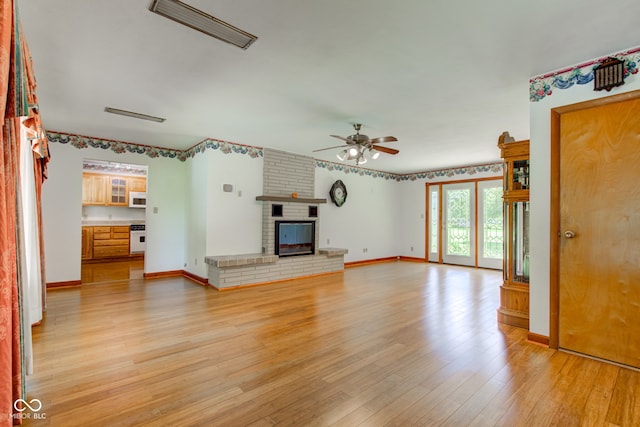 132 S First St, Jamestown, IN 46147 - unfurnished living room with a ceiling fan, light wood-style flooring, baseboards, and a brick fireplace