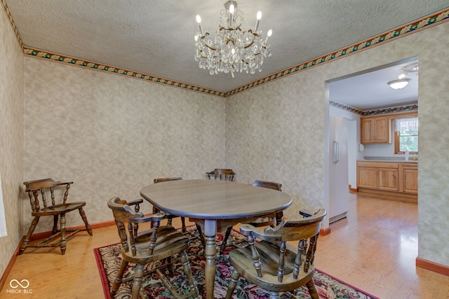 132 S First St, Jamestown, IN 46147 - dining area with light wood-style flooring, a textured ceiling, a chandelier, wallpapered walls, and baseboards
