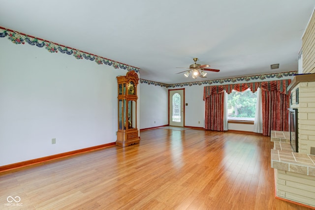 132 S First St, Jamestown, IN 46147 - unfurnished living room featuring ceiling fan, light wood finished floors, a brick fireplace, and baseboards